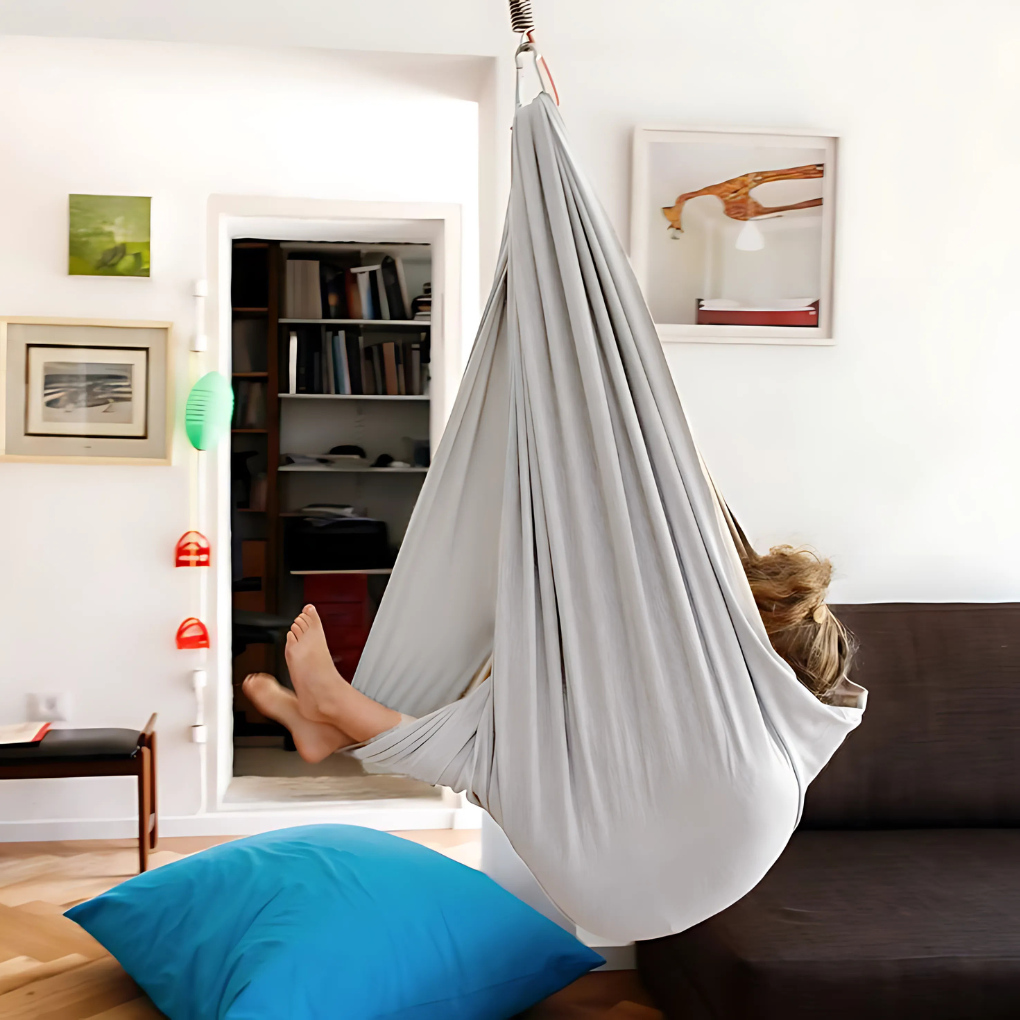 Kind geniet in zachte sensorische hangmatschommel; perfect voor kalmte, balans en leuke speelmomenten binnen/buiten.