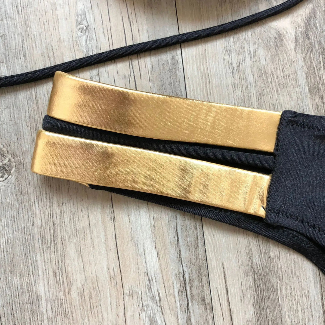 Blauwe dames bikini met gouden accenten. Stijlvolle strandmode, ideaal voor zomerse dagen aan het water.