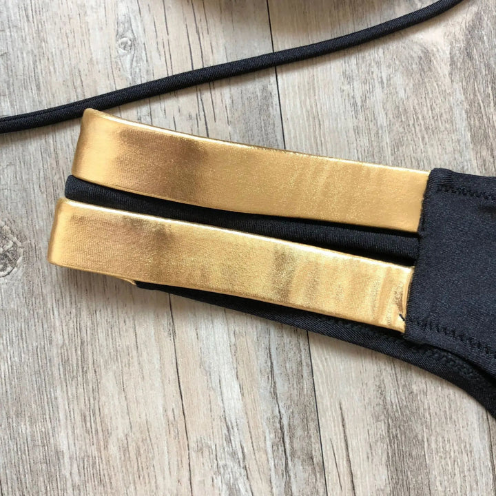 Blauwe dames bikini met gouden accenten. Stijlvolle strandmode, ideaal voor zomerse dagen aan het water.