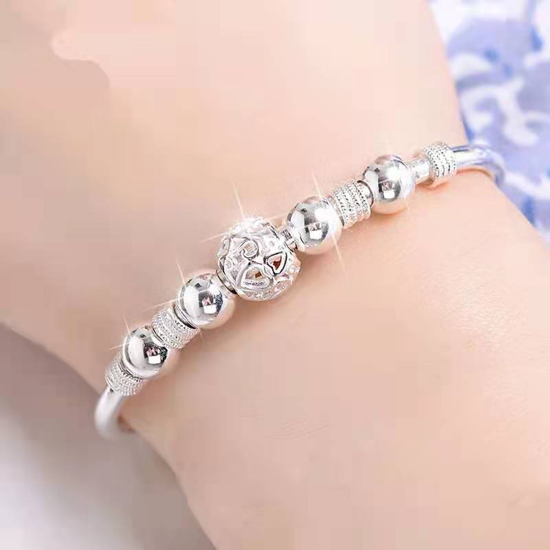 Damesarmband met elegante zilveren gelukskralen, perfect als modieus sieraad en accessoire.