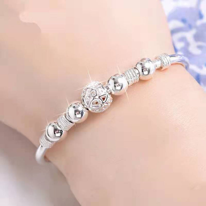 Damesarmband met elegante zilveren gelukskralen, perfect als modieus sieraad en accessoire.