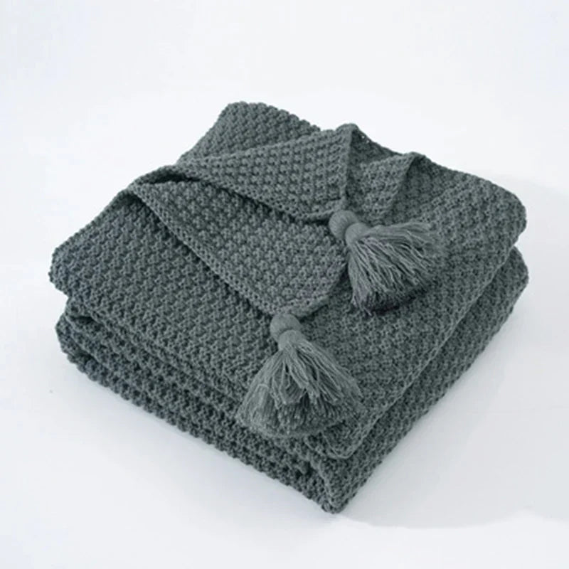 Gebreide wollen plaid met kwastjes in Scandinavische stijl, een comfortabel woonaccessoire voor thuis.