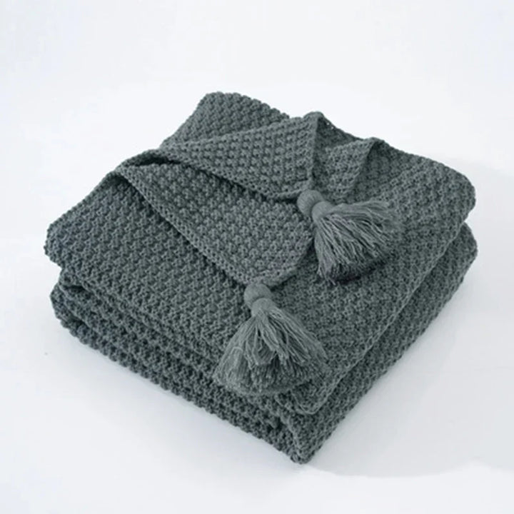 Gebreide wollen plaid met kwastjes in Scandinavische stijl, een comfortabel woonaccessoire voor thuis.