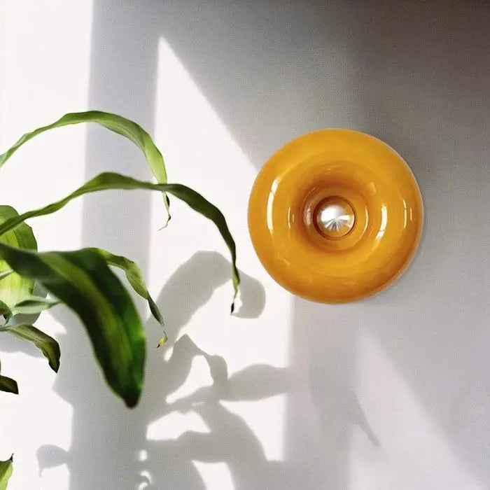 Design LED wandlamp in donut vorm, gemaakt van glas en metaal, geeft warm sfeerlicht.