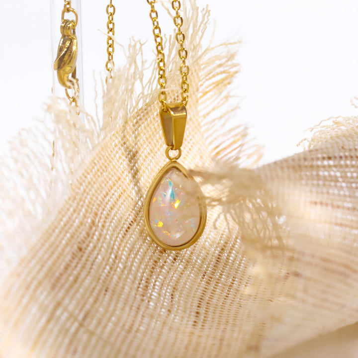 Betoverende opaal druppel hanger aan glanzende 18K gouden ketting. Elegantie voor elke gelegenheid.
