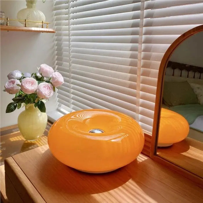 Energiezuinige LED donut tafellamp in oranje glas, trendy en functioneel voor slaapkamer.