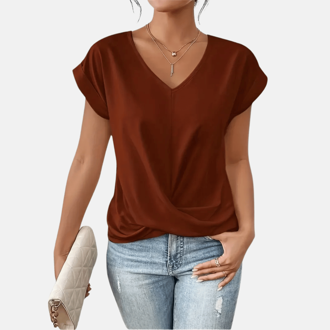 Dames draagt een zachte V-hals blouse met gedrapeerde zoom en korte mouwen, perfect voor een zomerse look.