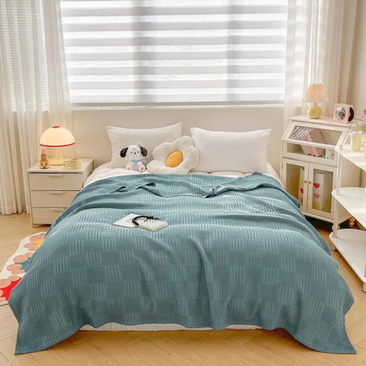 Comfortabele biologisch katoenen wafeldeken in neutrale kleur op bed, zacht en stijlvol huistextiel.