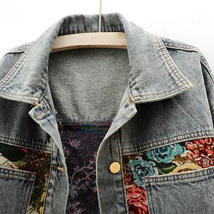 Elegant blauw dames spijkerjasje met gedetailleerde bloemenprint, perfect voor een unieke, modieuze stijl.