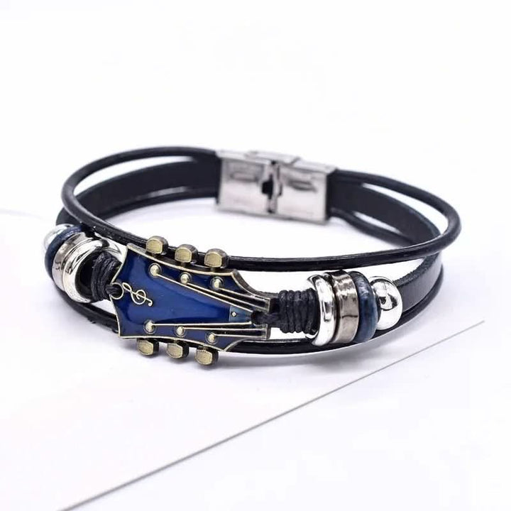 Gedetailleerde foto van de gitaarbedel op de leren armband, benadrukt vakmanschap en stijl.
