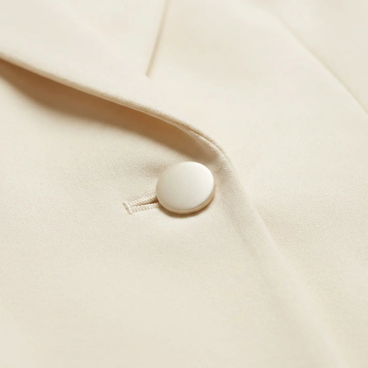 Elegant getailleerd dames broekpak met slanke pasvorm en flared broek, creëert een moderne en vrouwelijke silhouet.