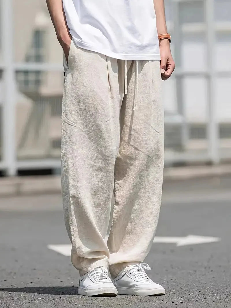 Man draagt comfortabele beige baggy linnen broek met elastische taille; perfecte casual zomerkleding voor heren.