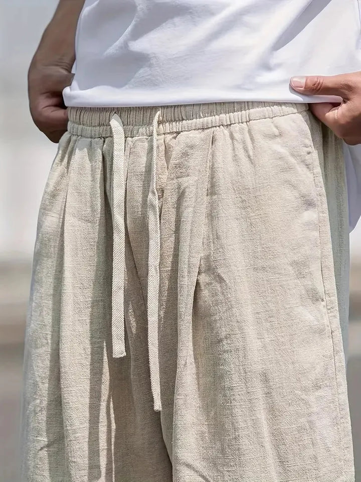 Gedetailleerd beeld van de beige baggy linnen broek, benadrukt de zachte stof en comfortabele elastische taille.