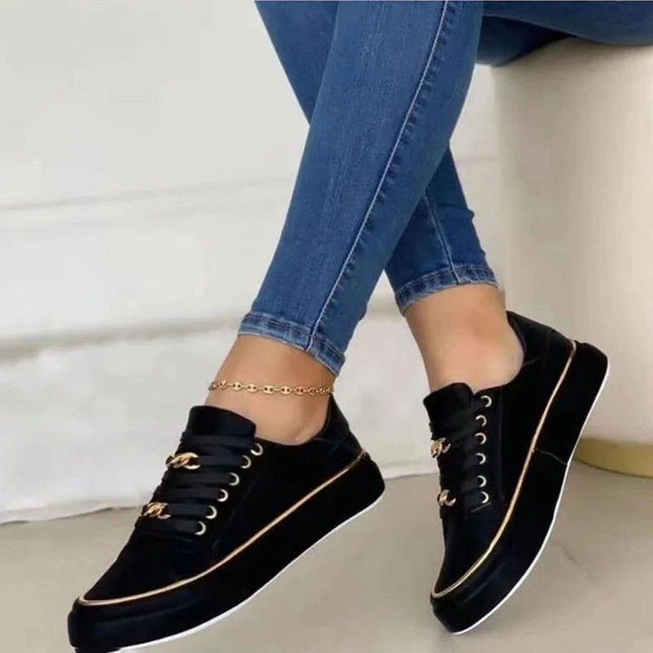 Casual zwarte en witte damessneakers met subtiele gouden accenten, ideaal voor modebewuste vrouwen die comfort zoeken.