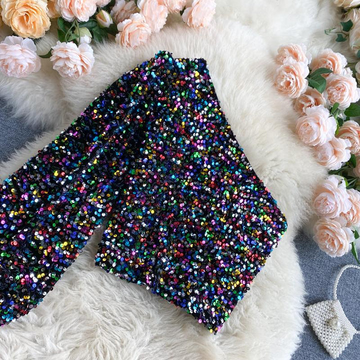 Model poseert met de feestelijke dames glitter one-shoulder top voor een chique look.