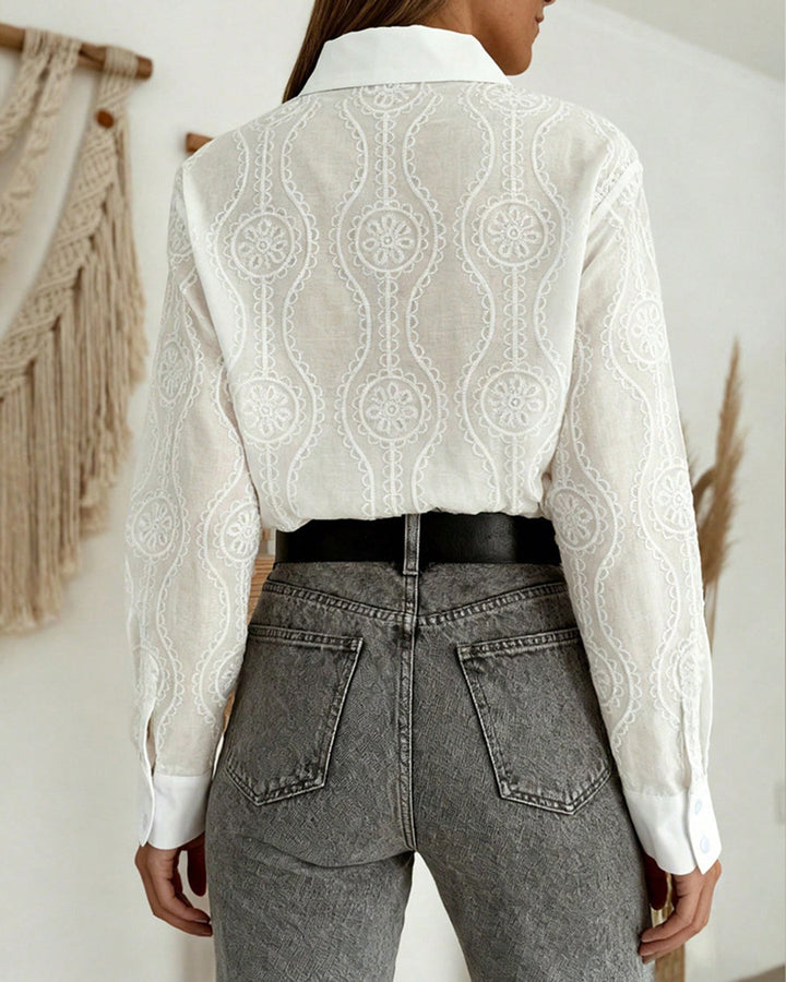 Witte elegante damesblouse met geometrisch dessin, lange mouwen en stijlvolle knoopkraag, comfortabel en chic.
