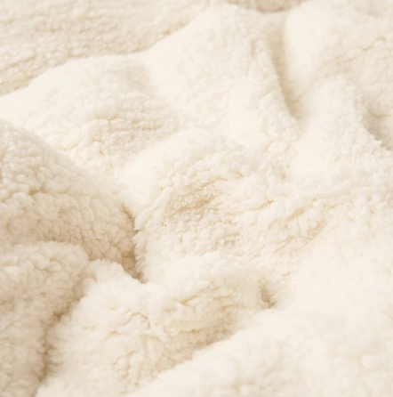 Stapel van zachte SoftHug fleecedekens in diverse kleuren, warm en decoratief voor elk interieur.