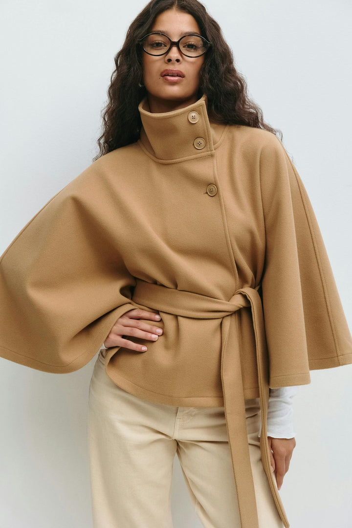 Dames wintermode: comfortabele capejas met hoge kraag en tailleceintuur voor een elegante look.