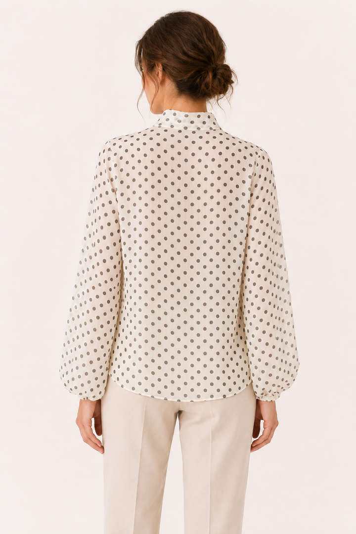 Veelzijdige damesblouse in beige met subtiele stippenprint, charmant strikdetail en trendy pofmouwen.