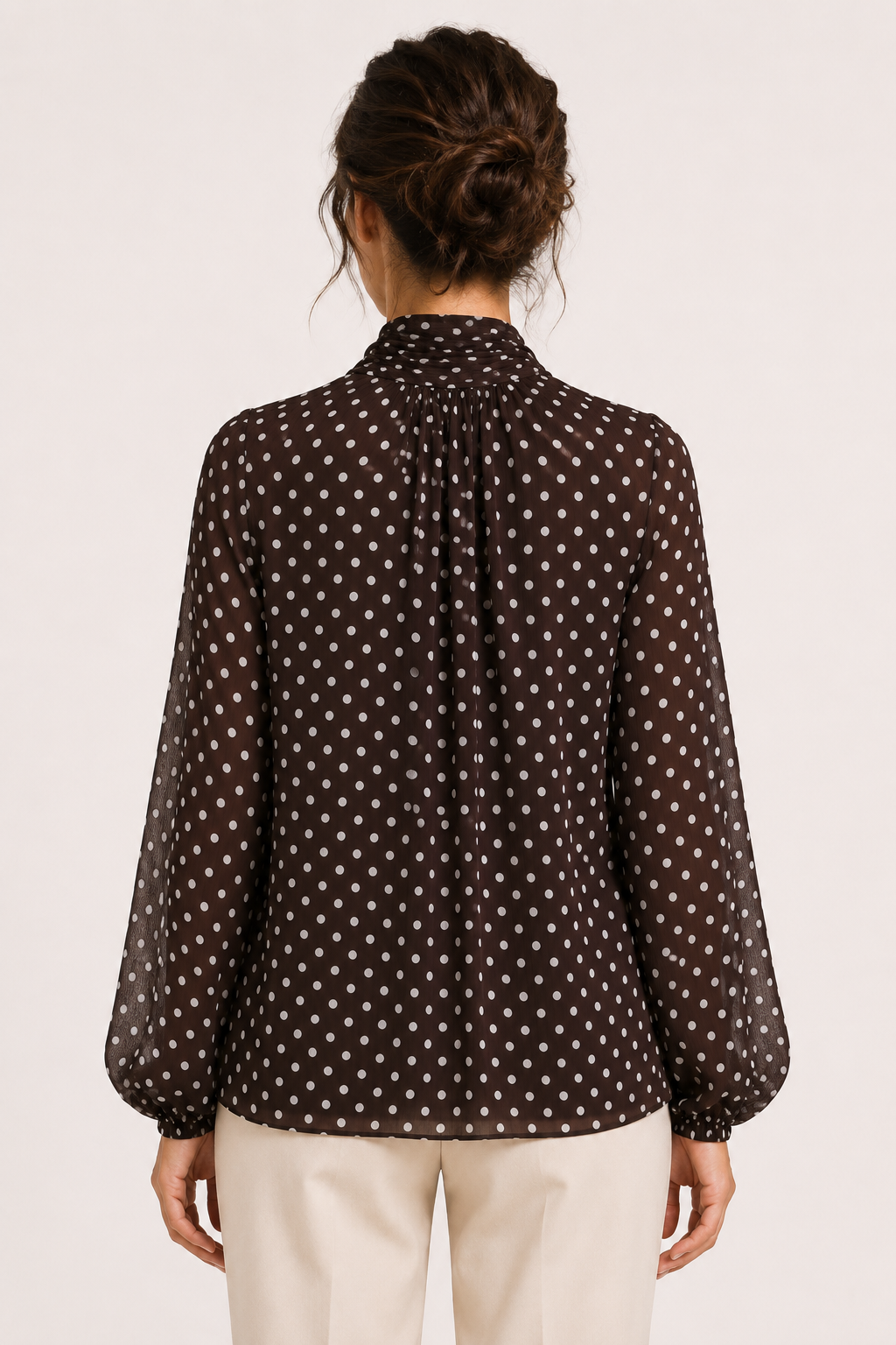 Damesblouse met beige/bruine stippenprint, strikdetail en pofmouwen. Modieuze en veelzijdige kleding.
