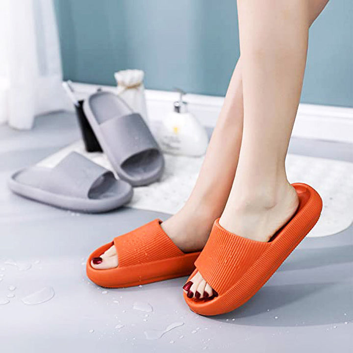 Man draagt comfortabele zwarte unisex wolk slippers, voor dagelijks loopcomfort thuis.
