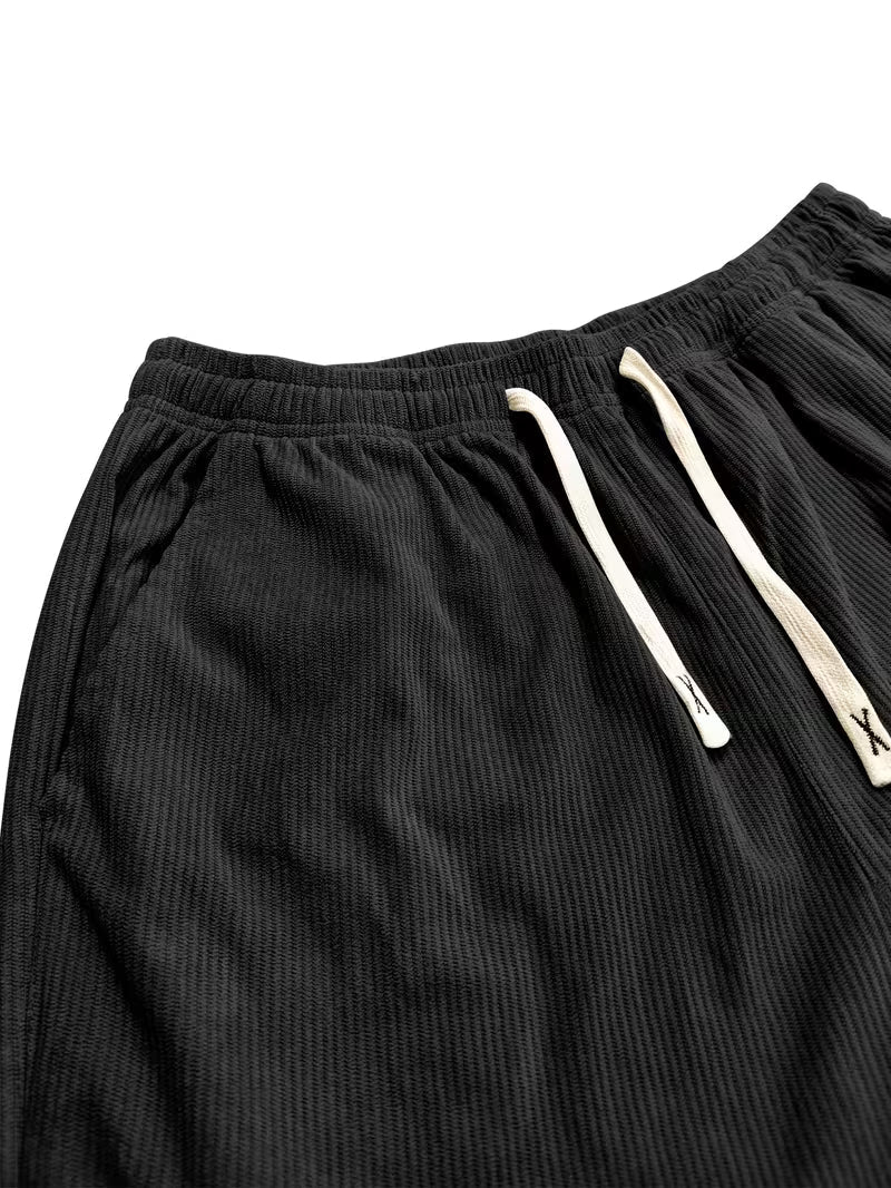 Gedetailleerde foto van heren corduroy broek, rechte pijpen, losse pasvorm, focus op textuur en stof.