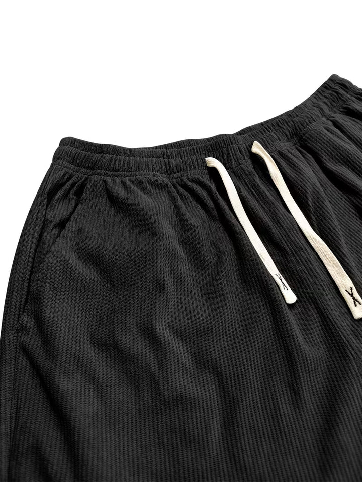 Gedetailleerde foto van heren corduroy broek, rechte pijpen, losse pasvorm, focus op textuur en stof.