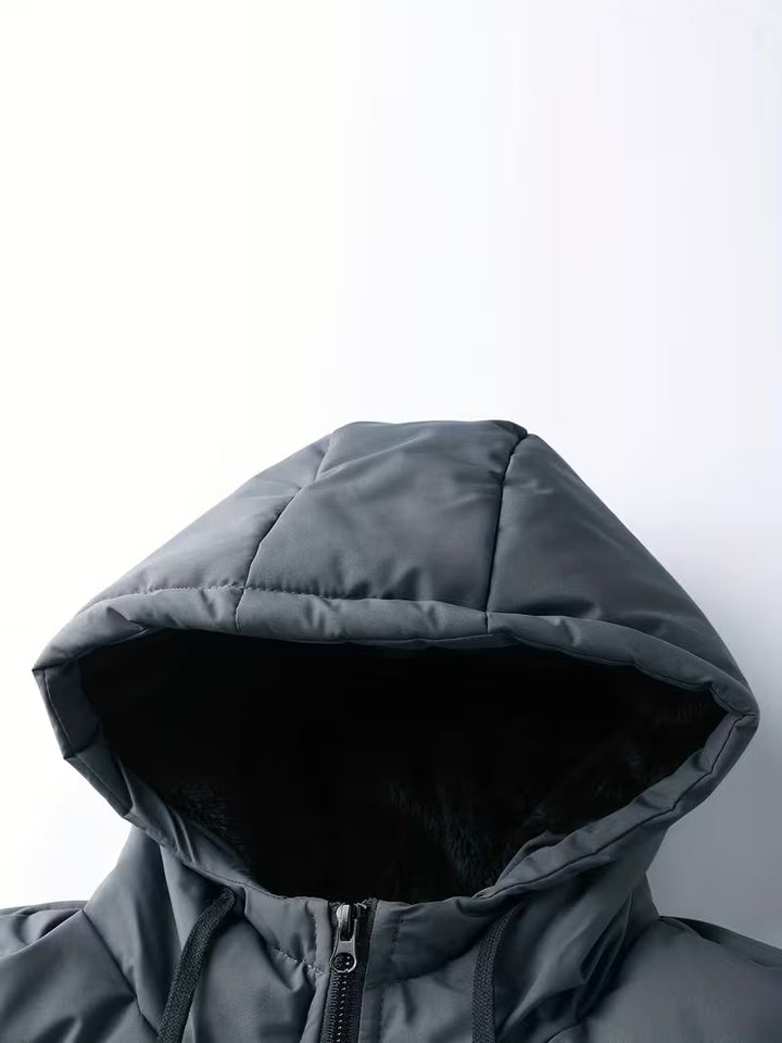 Man draagt een warme, casual grijze heren gewatteerde parka met capuchon en fleece voering buiten.