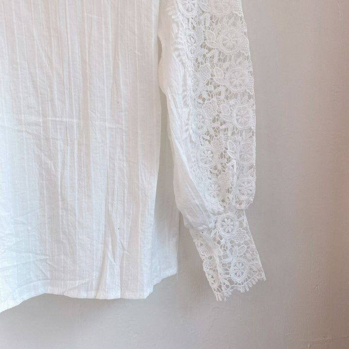 Textuur van de klassieke damesblouse, met focus op de kanten details en de soepele stof van de pofmouwen.
