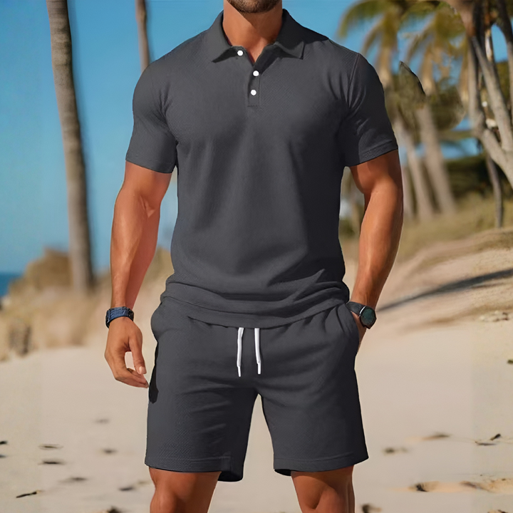 Man draagt ademende tweedelige set met korte mouw en shorts, ontspannen en comfortabel voor zomerse dagen.