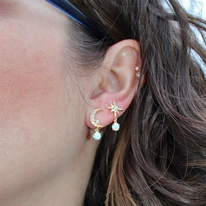 Gedetailleerde gouden oorbellen met maan en ster, versierd met glanzende opaal. Elegante dames juwelen.