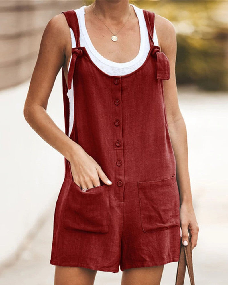 Korte dames zomerjumpsuit, effen met speelse knoopjes en handige zakken. Perfecte casual mode.