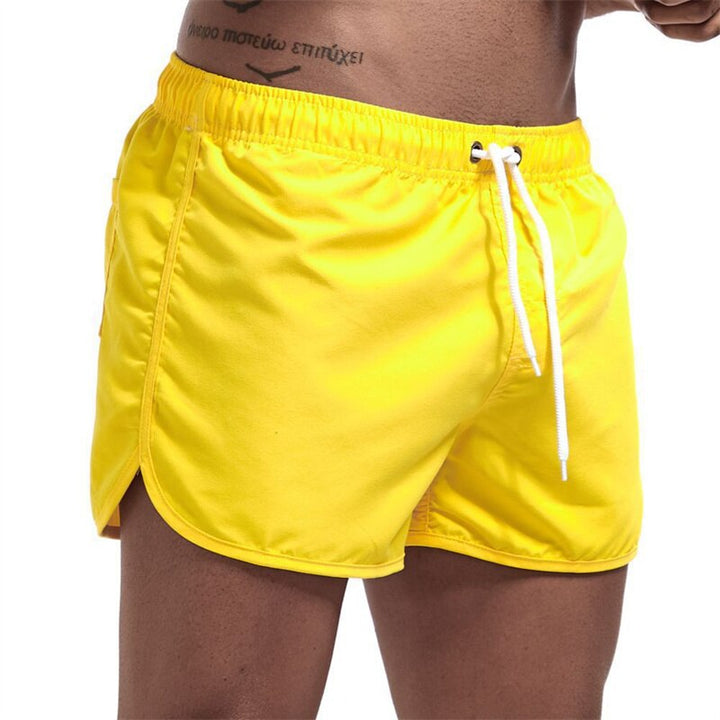 Man draagt stijlvolle heren zwemshort Ryan op het strand, een trendy en comfortabele keuze voor zomerkleding.