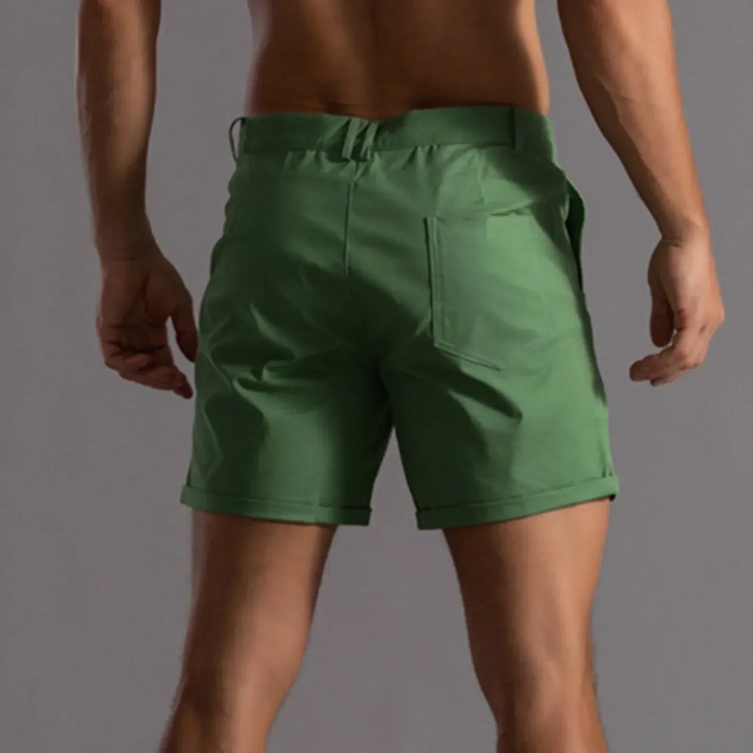 Model poseert met trendy heren chino shorts en zomeraccessoires. Casual look.