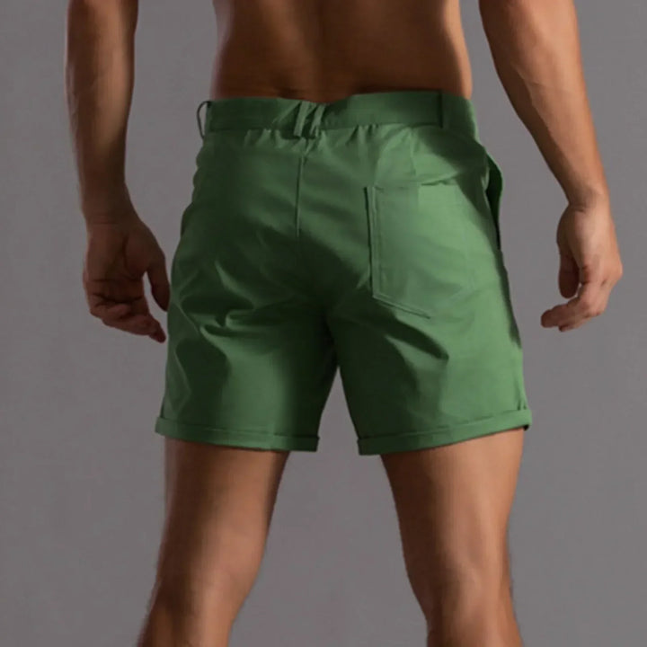 Model poseert met trendy heren chino shorts en zomeraccessoires. Casual look.