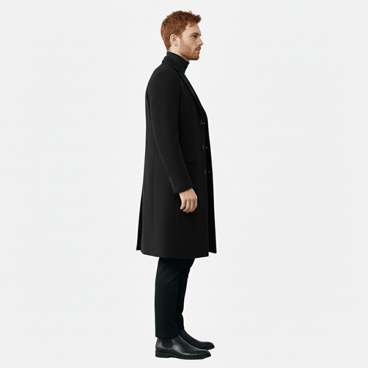 Man draagt de elegante herenmantel Phoenix, toont de lange pasvorm en knoopdetails.
