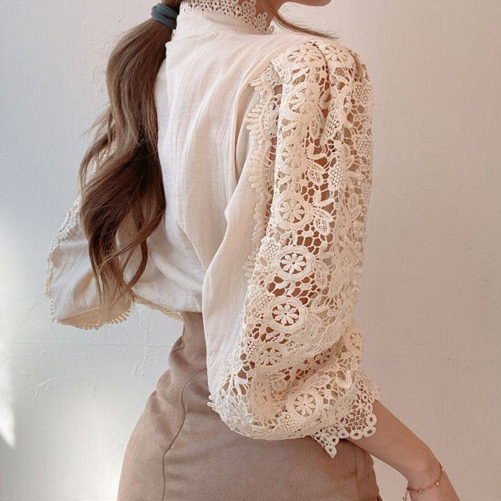 Gedetailleerde weergave van de prachtige kanten details langs de halslijn van deze modieuze damesblouse.