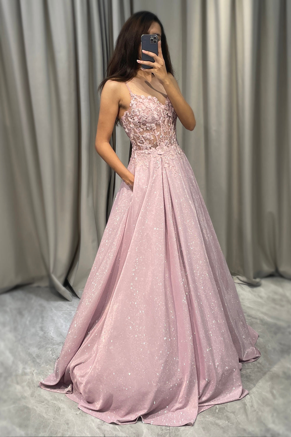Model draagt een betoverende glinsterende blush roze A-lijn galajurk, ideaal voor een speciale avond.