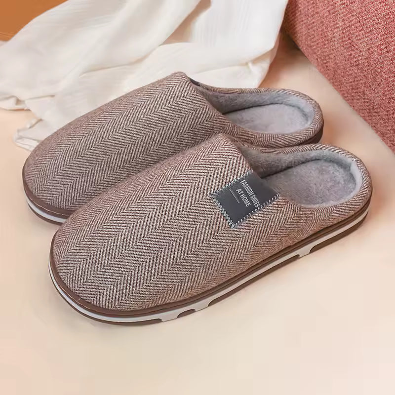Paar luxe bruine unisex pantoffels op een zachte ondergrond, uitnodigend voor ultiem comfort en warmte.