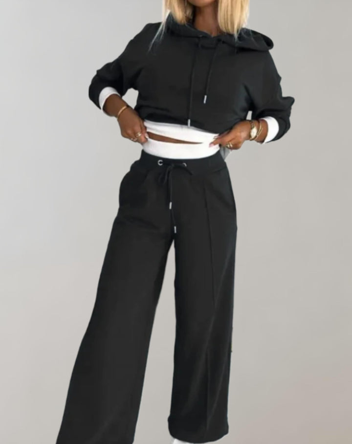 Modieuze dames reisoutfit Savannah: casual hoodie en flowy wijde broek, perfect voor een ontspannen look.