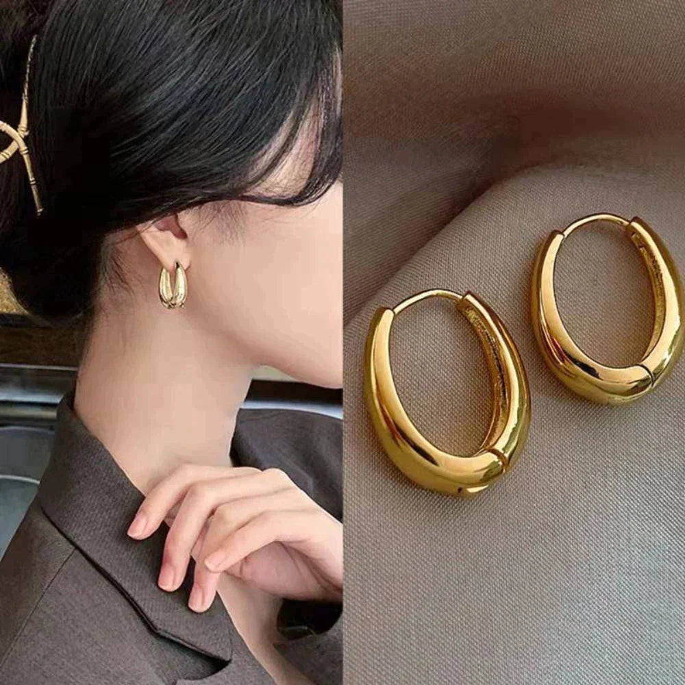 Glanzende gouden oorringen voor dames. Klassieke elegante sieraden die elke outfit completeren.