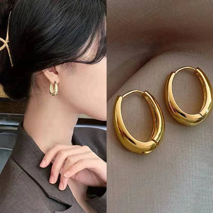 Glanzende gouden oorringen voor dames. Klassieke elegante sieraden die elke outfit completeren.