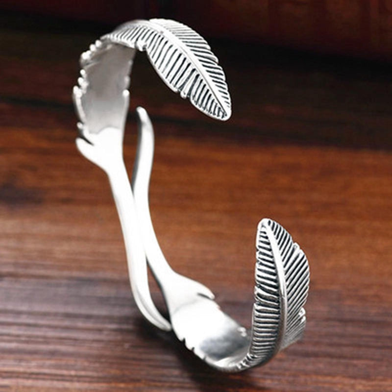Verzilverde unisex armband met levensechte veerbedels. Verstelbaar en elegant sieraad, een uniek accessoire.
