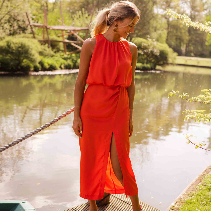 Stijlvolle dames midi jurk in rood met hoge halslijn, mouwloos design en split, geschikt voor feestjes.