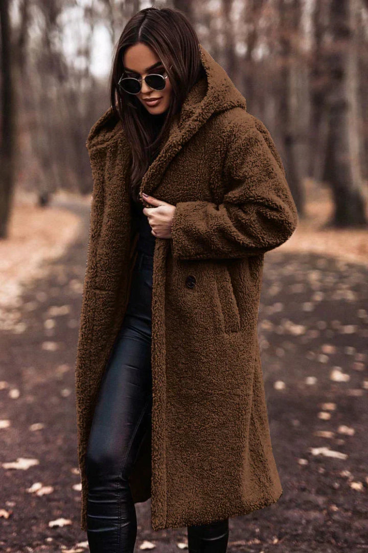 Vrouw draagt een oversized Lumi teddyjas met capuchon. Warme en comfortabele winterjas, perfect voor buitenactiviteiten.