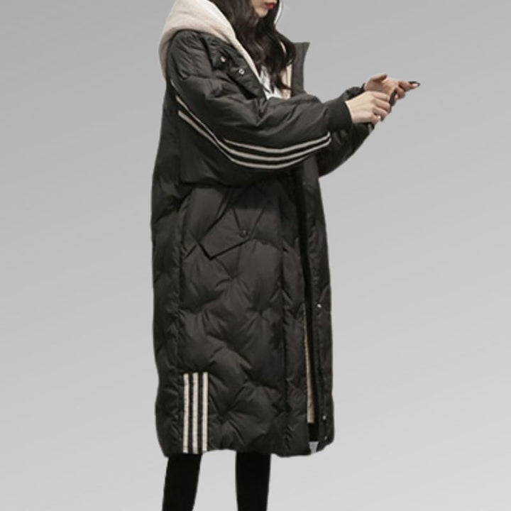 Model draagt oversized gewatteerde damesjas Kimberly, met capuchon, lange pasvorm, comfortabel en modieus.