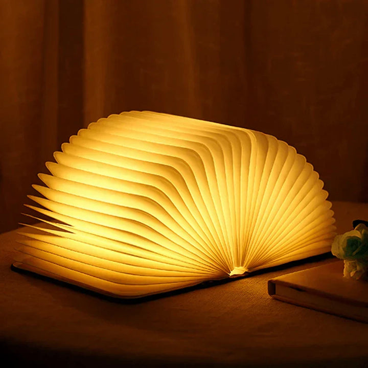 Stijlvolle StoryGlow opvouwbare boekenlamp op een boekenplank, als LED leeslamp en decoratie.