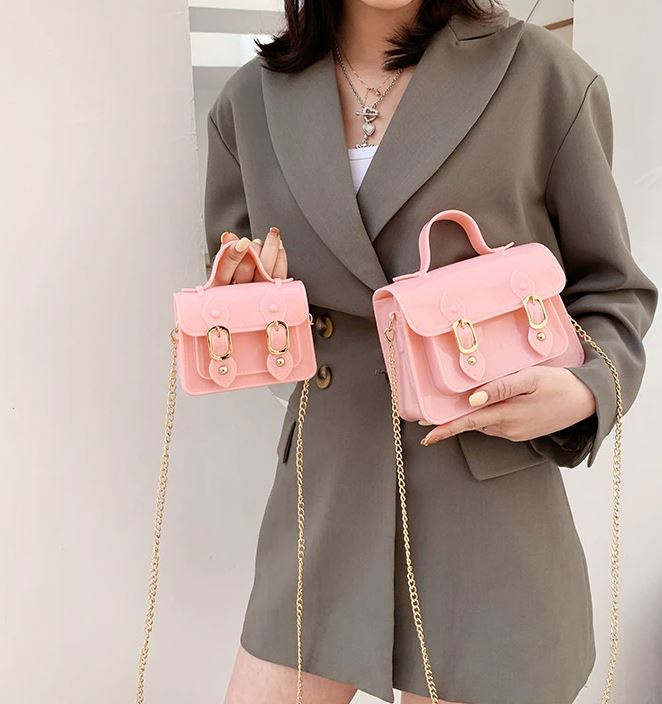 Vrouw draagt een elegante compacte jelly crossbody tas met chain details.