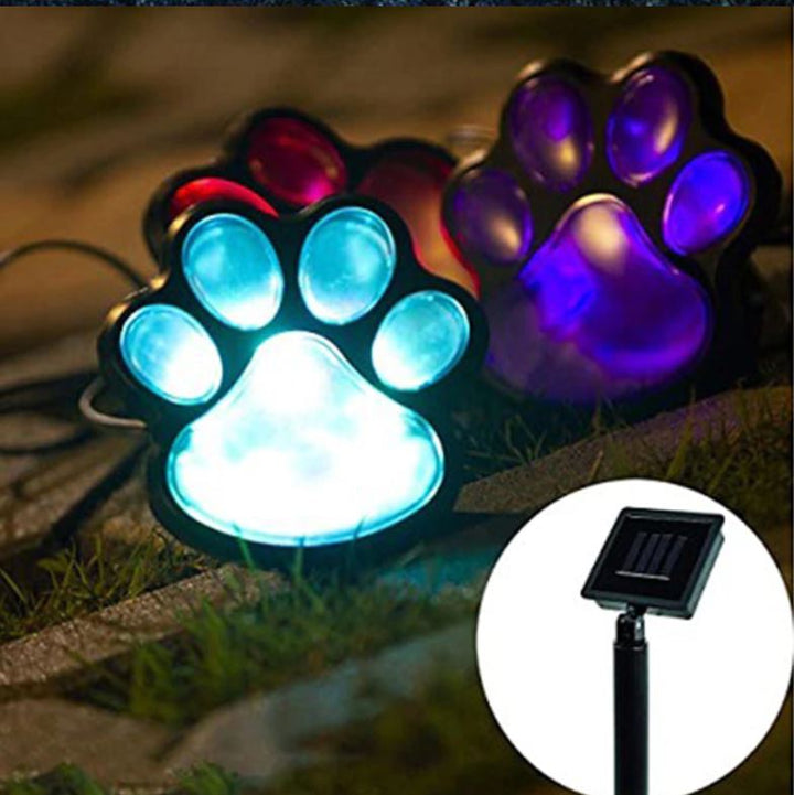 Sfeervolle LED hondenpoot lamp verlicht een tuinpad 's avonds, aangedreven door zonne-energie.