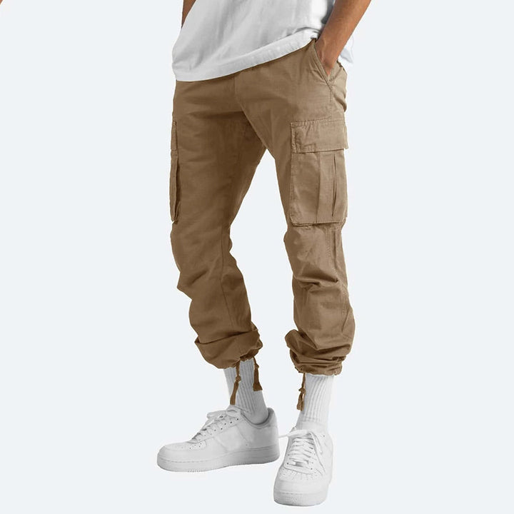 Model draagt comfortabele heren cargo zomerbroek in een ontspannen zomerse setting.